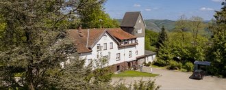 Gut Sassenscheid Frontalansicht eines Landhauses mit Turm am rechten Rand, Bäume und Wiesen außen herum.