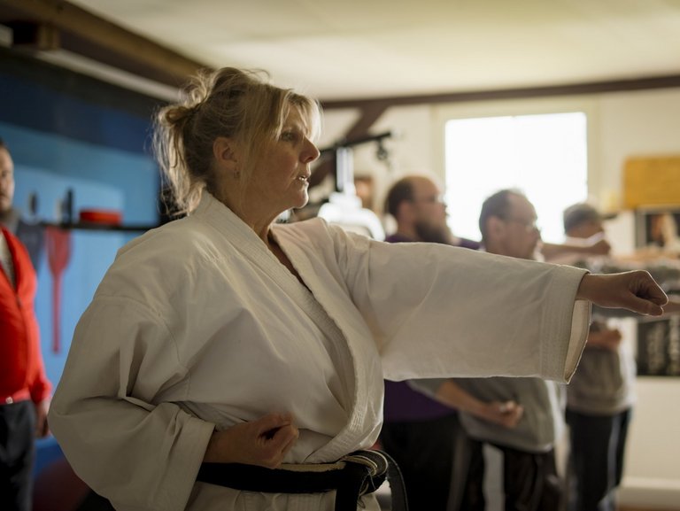 Eine Karatetrainerin trainiert mit vier Männern.